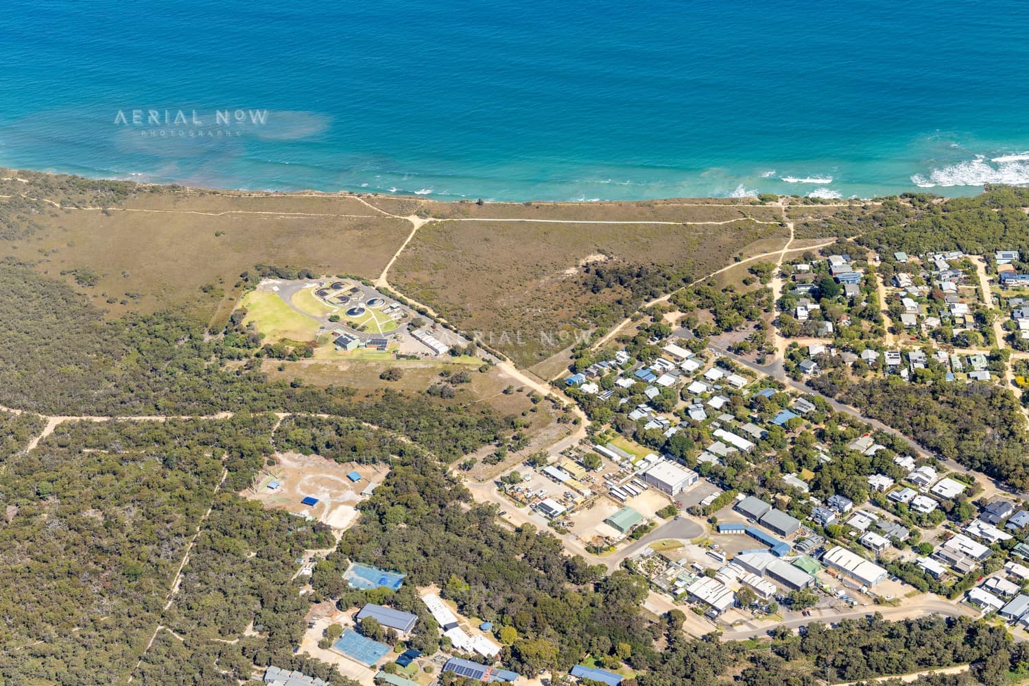 Aerial view of the Anglesea coastline in Victoria with blue ocean, coastal heathland, walking tracks and residential streets near Simmons Court.