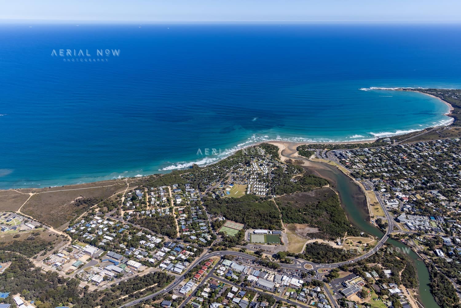 Aerial view of the Anglesea River mouth, Anglesea Beach, coastal township, ocean shoreline and surrounding streets in Anglesea, Victoria.