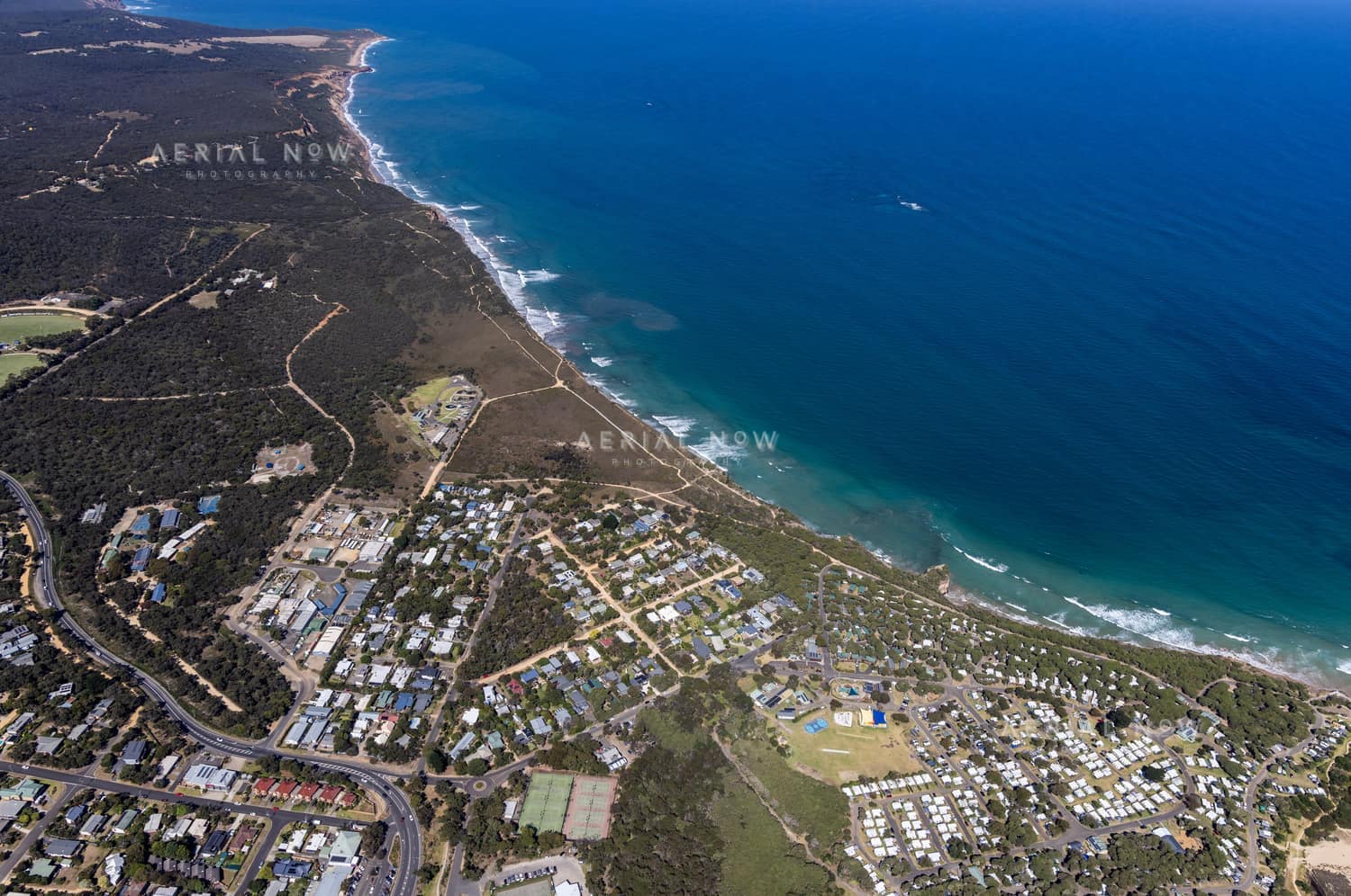 Aerial view of Anglesea coastline, residential streets, bushland reserves and ocean surf in Anglesea, Victoria.