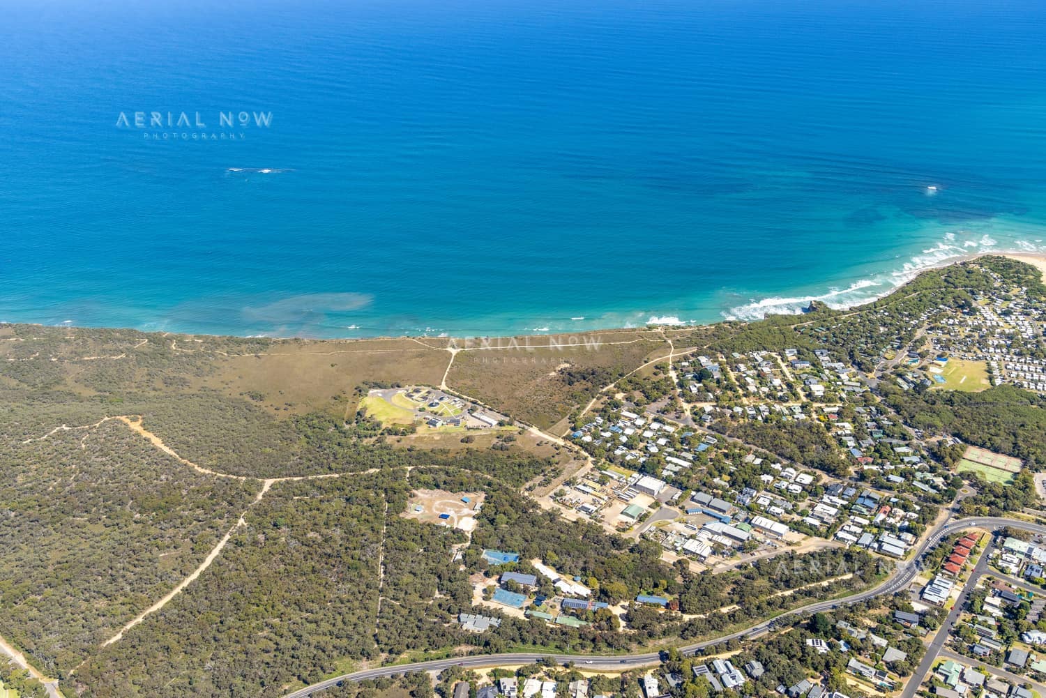Aerial view of the Anglesea coastline with residential estates, coastal bushland, access tracks and blue ocean water in Anglesea, Victoria.