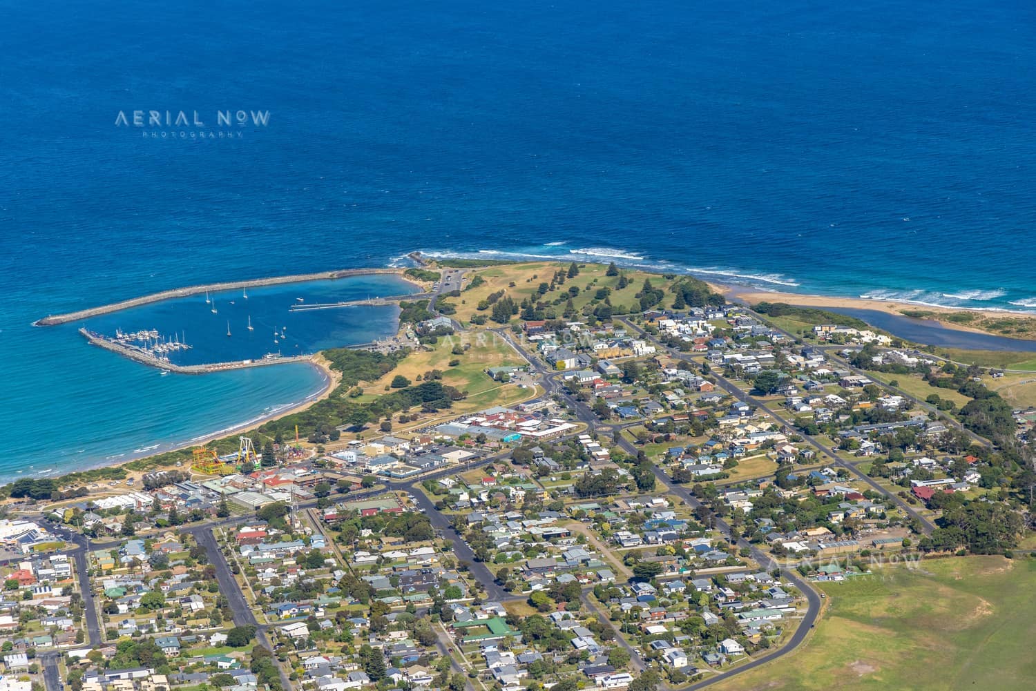 Aerial view of Apollo Bay Harbour, the marina breakwaters, residential streets and coastline at Apollo Bay on Victoria's Great Ocean Road.