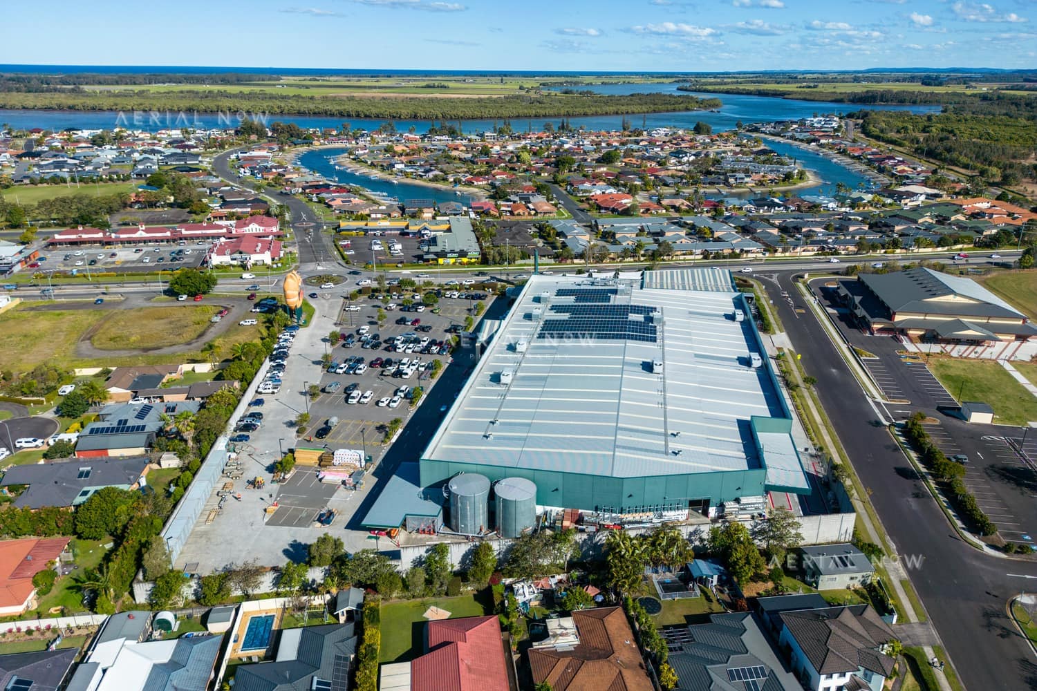 Aerial view of the Big Prawn beside Bunnings Warehouse in West Ballina, with canals, homes and the Richmond River in the background.