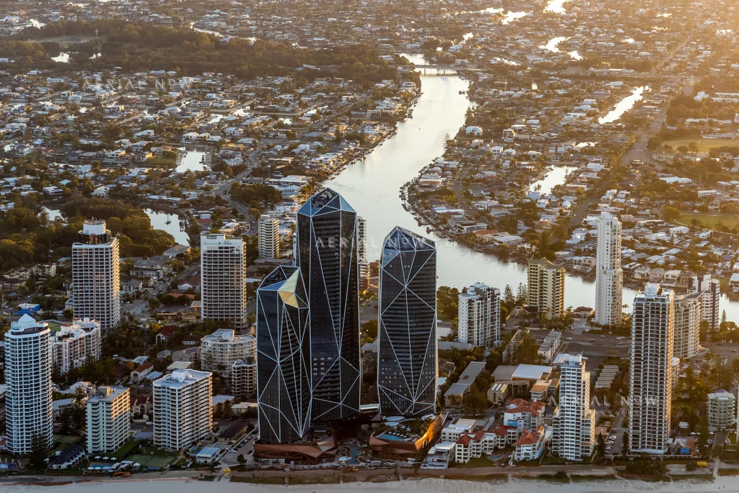 Aerial view of the Jewel Gold Coast towers on the Surfers Paradise beachfront with high-rise buildings, beach sand and inland Gold Coast waterways behind.