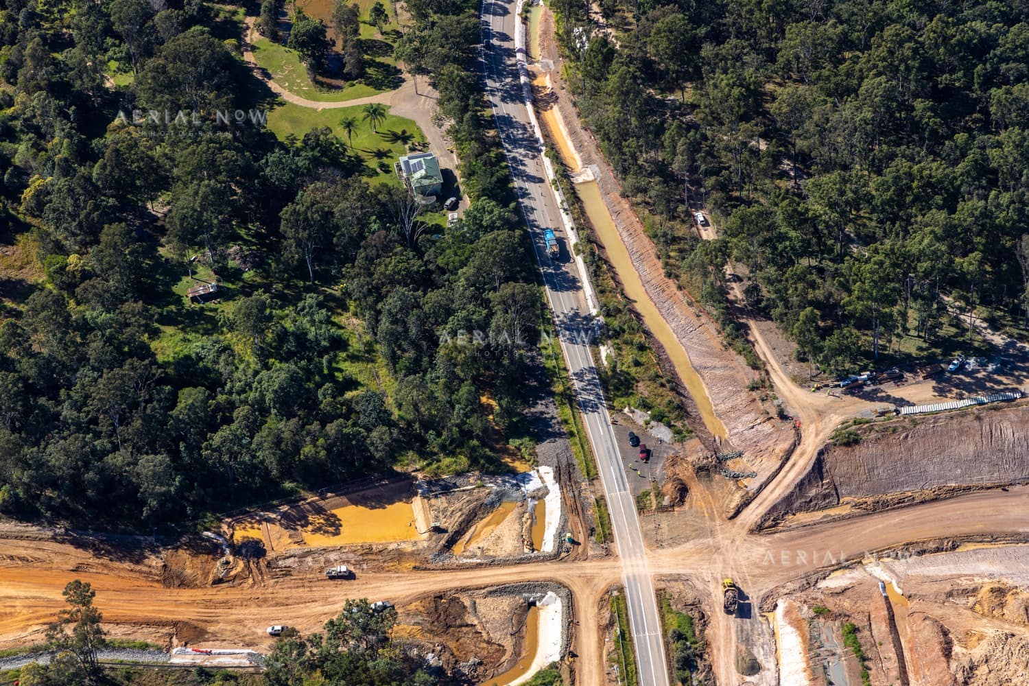 Aerial view of road construction along Gympie Connection Road in Victory Heights, Queensland, with earthworks, vehicles, bushland and nearby properties.