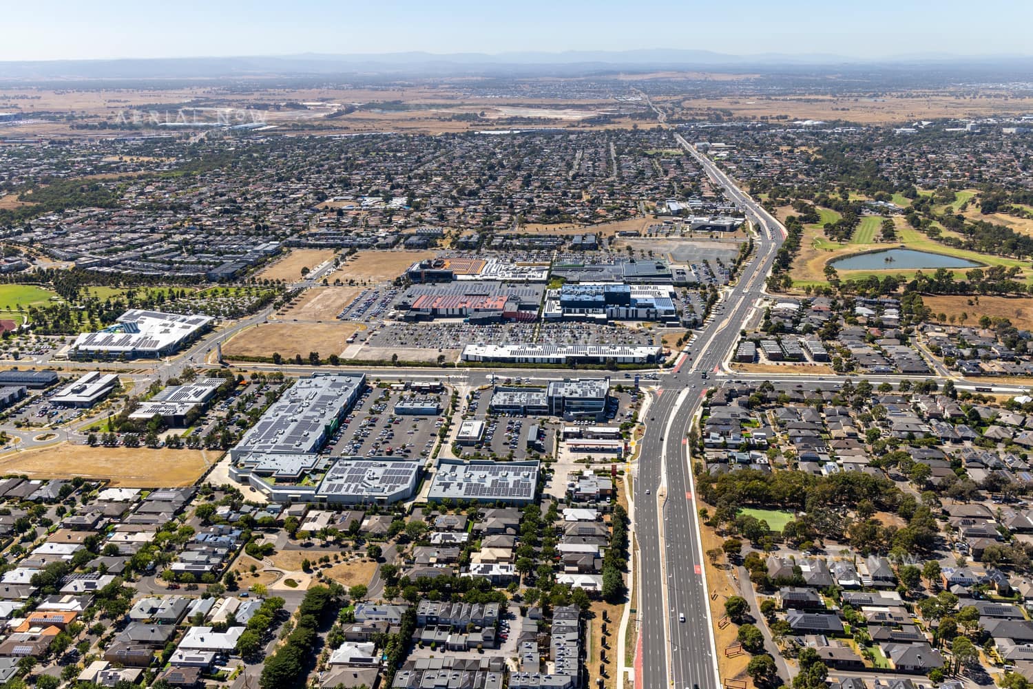 Aerial view of the Craigieburn Road commercial precinct in Craigieburn, with major roads, shopping centre car parks, housing estates and parkland visible.
