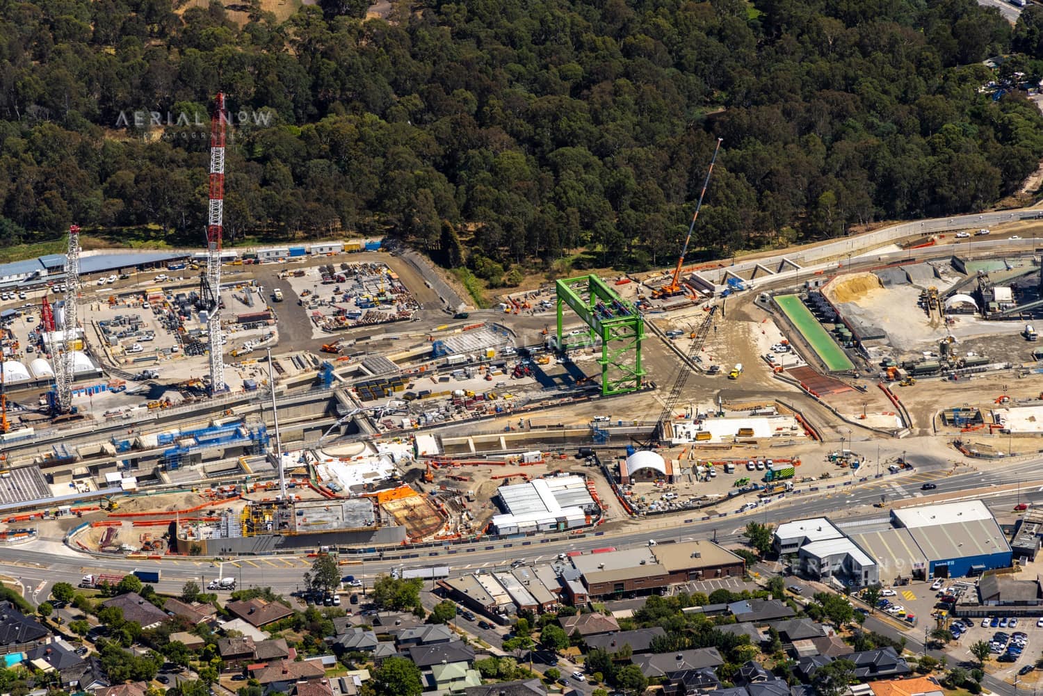 Aerial view of North East Link construction works in Bulleen VIC, showing cranes, work zones, temporary structures, roads and surrounding bushland.