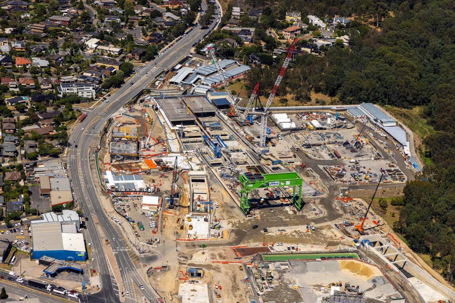 Aerial view of the North East Link construction site in Bulleen VIC, showing cranes, work zones, roadworks, surrounding suburban streets and bushland.