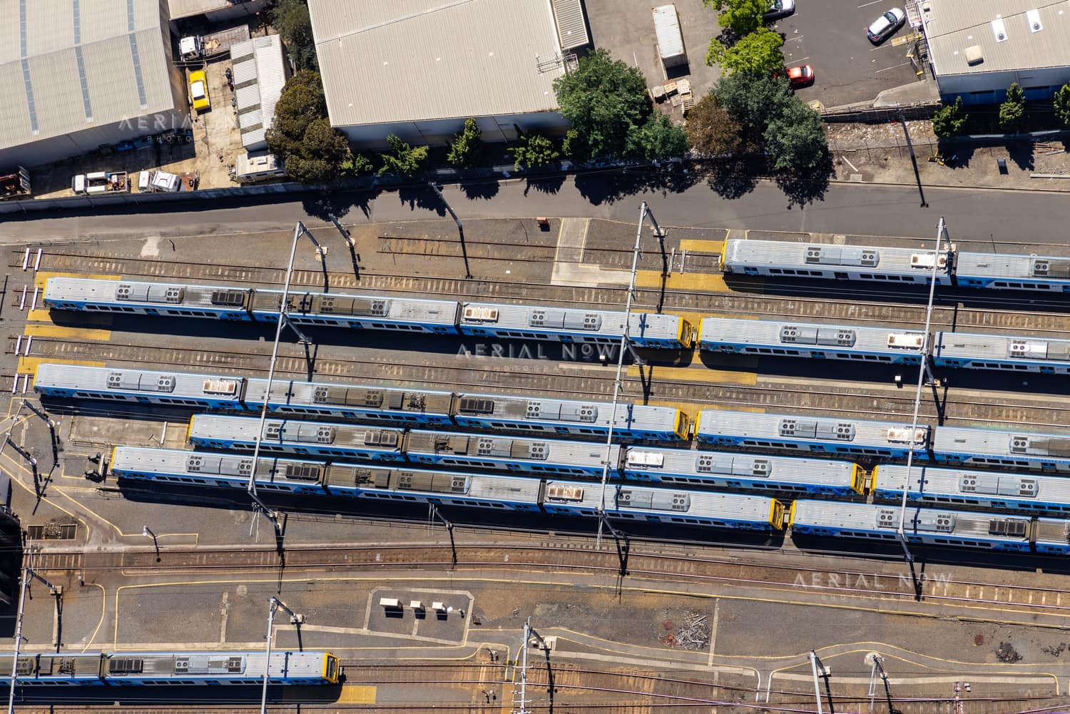 Aerial view of the Epping railway stabling yard in Epping VIC, with multiple suburban trains parked on parallel tracks beside Railway Road and industrial buildings.