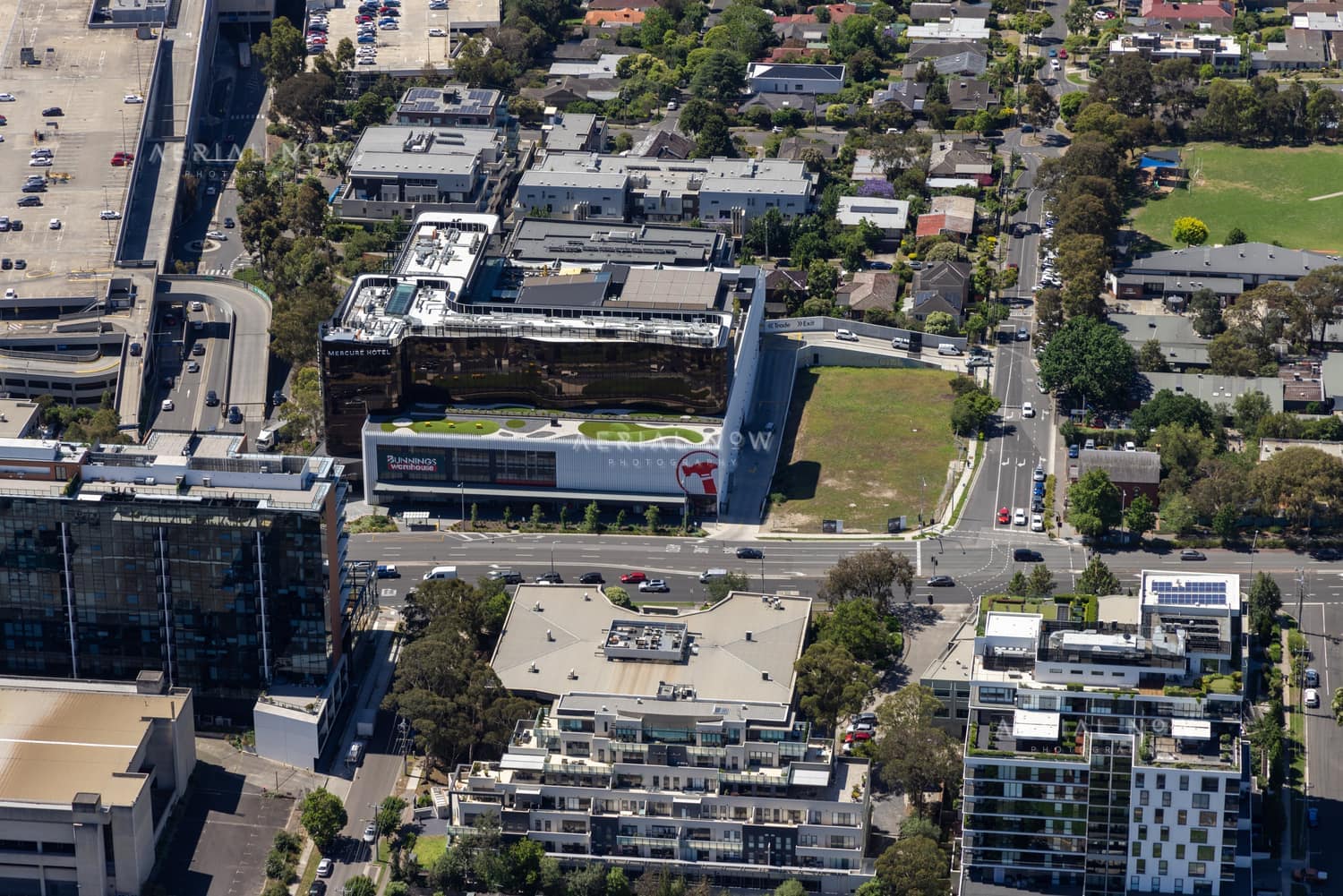 Aerial view of Westfield Doncaster beside Doncaster Road in Doncaster, showing the shopping centre edge, commercial buildings, apartments, car parks, traffic and surrounding suburban streets.