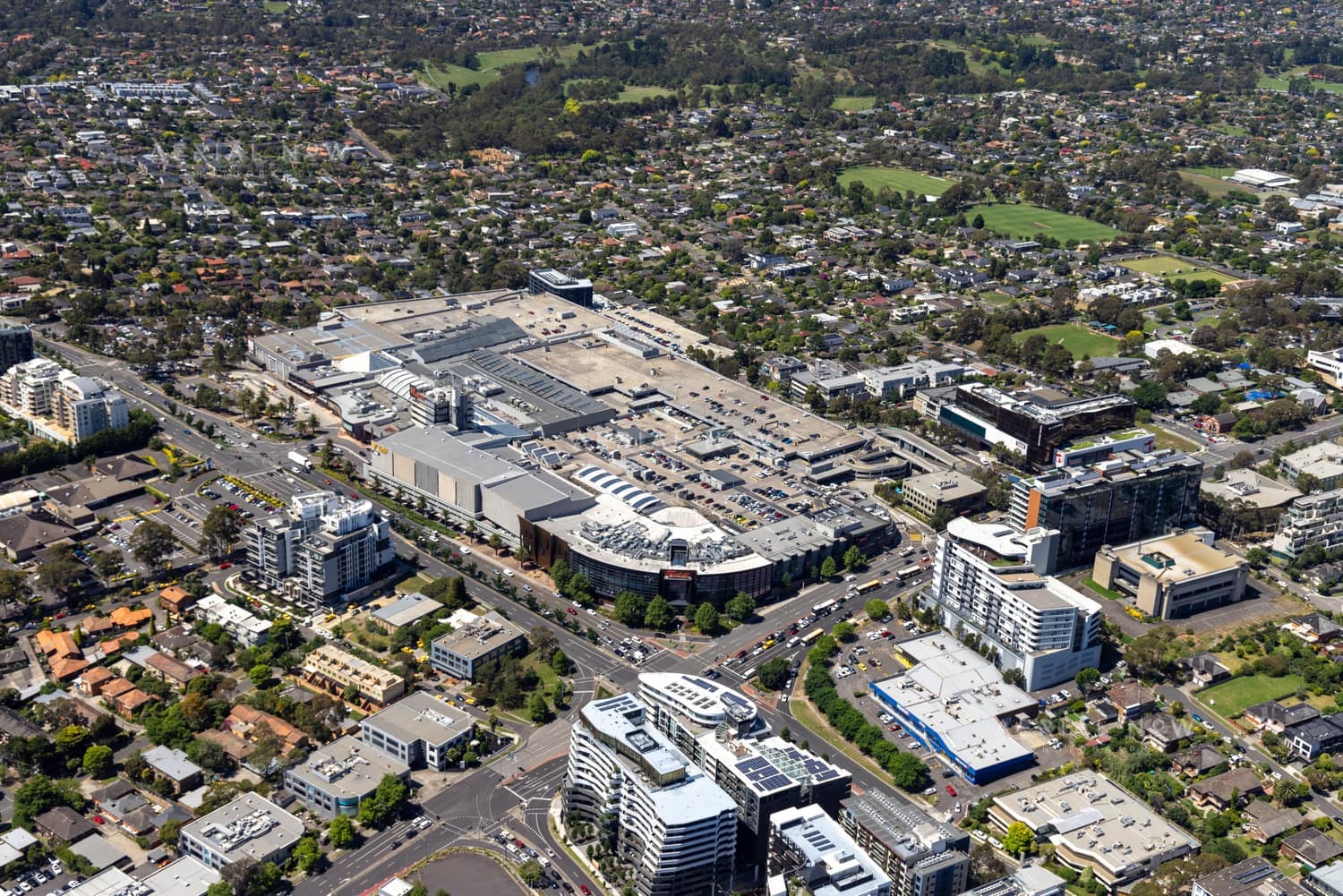 Aerial view of Westfield Doncaster shopping centre with rooftop car parks, surrounding apartment buildings, Doncaster Road and suburban streets in Doncaster, Victoria.