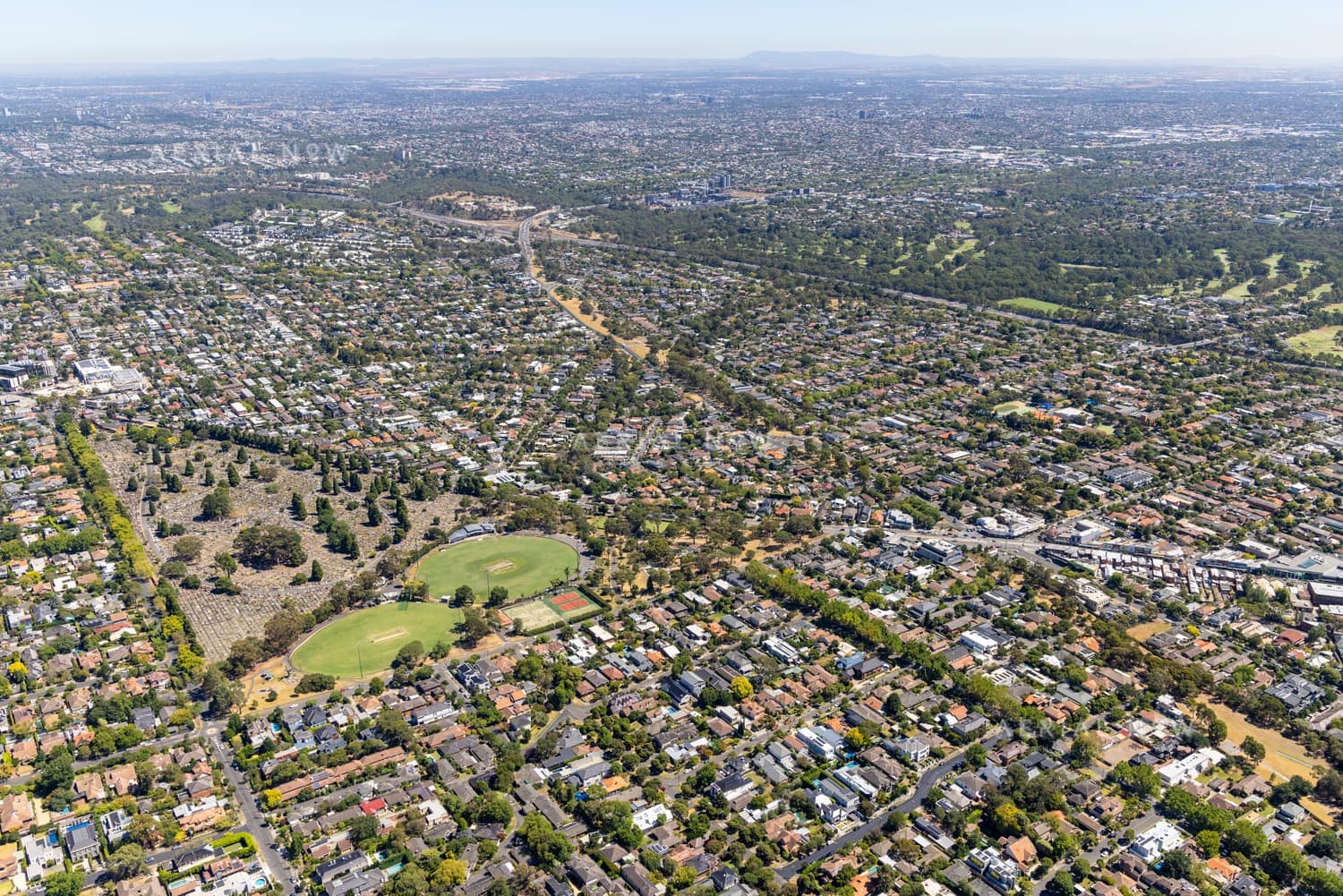 Aerial view of Boroondara General Cemetery in Kew, with surrounding residential streets, sports ovals, parkland and Melbourne suburbs extending into the distance.