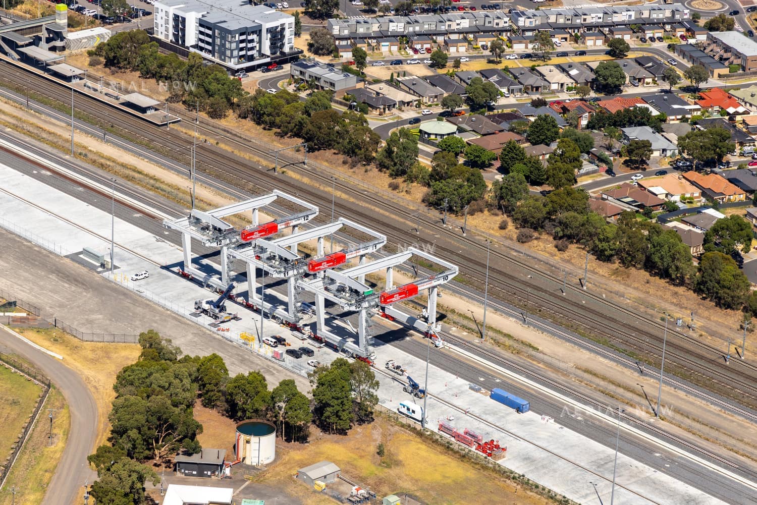 Aerial view of the Somerton rail freight terminal area with gantry cranes, rail sidings, adjacent tracks, industrial land and nearby housing in Somerton, Victoria.
