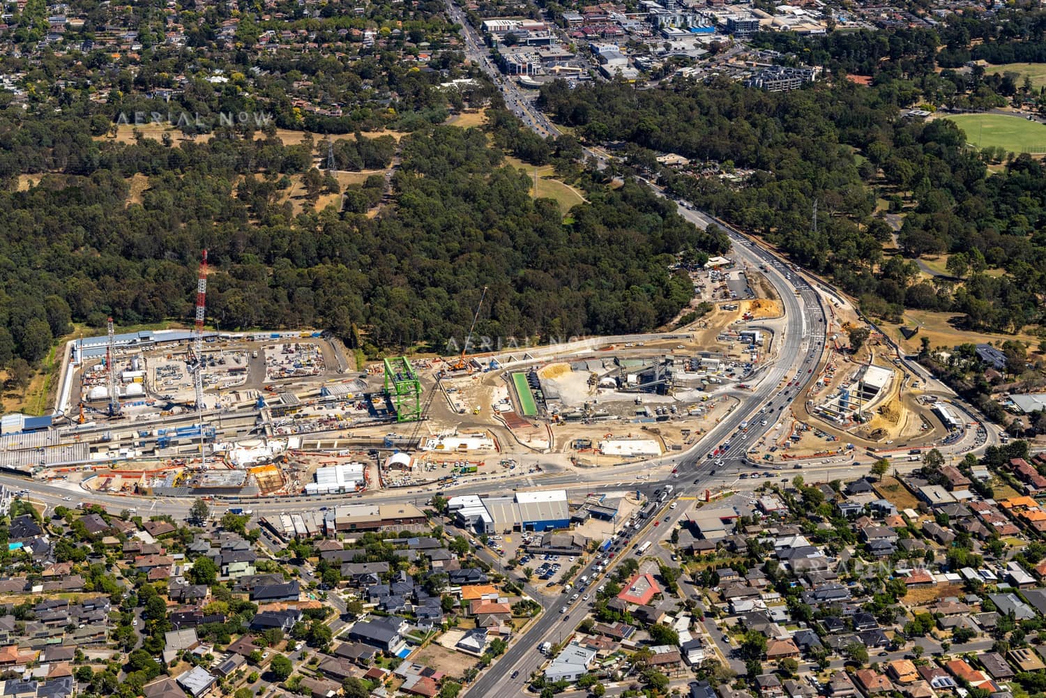Aerial view of North East Link construction works in Bulleen, with road alignments, work zones, homes, parkland and suburban streets.