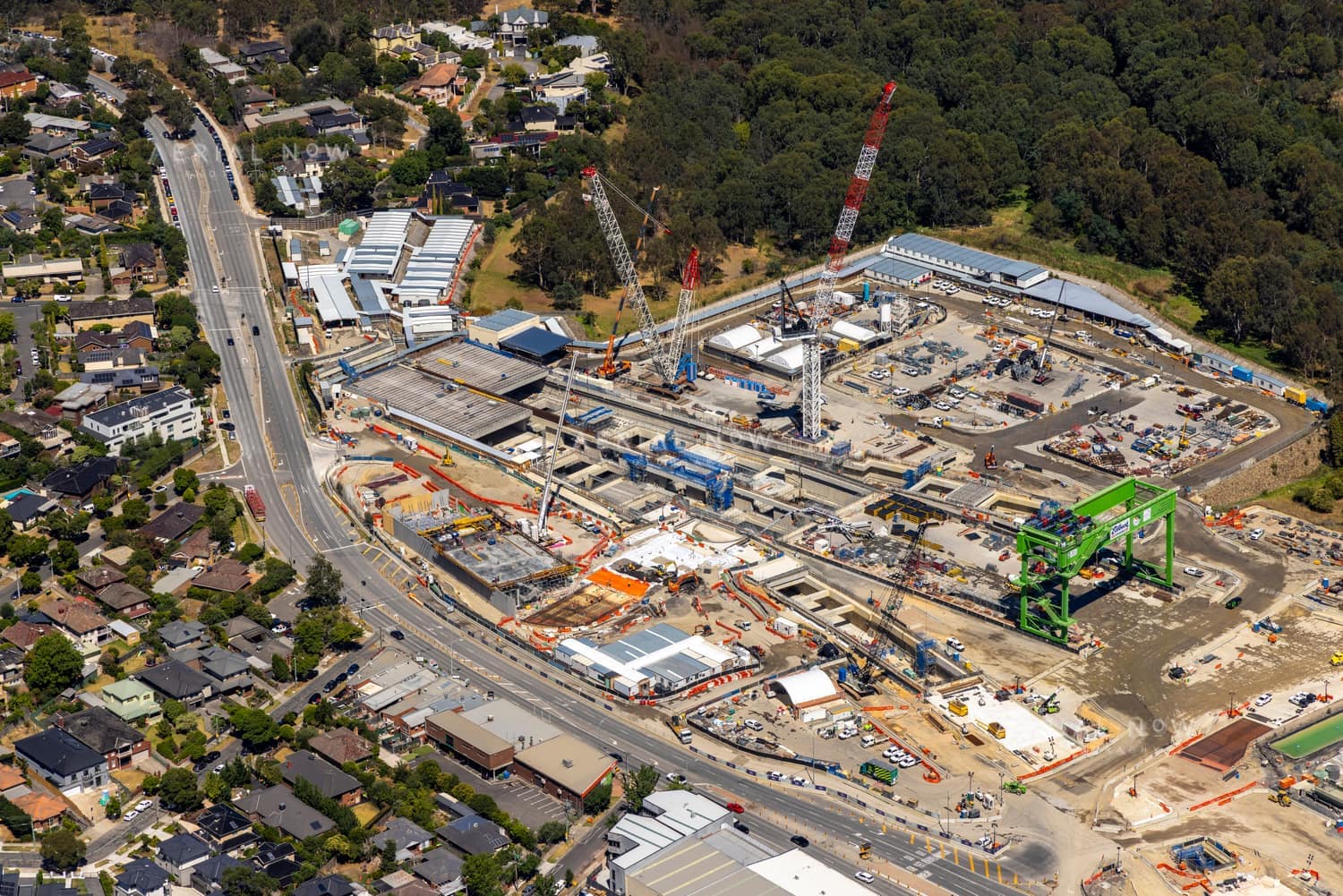 Aerial view of the North East Link construction site in Bulleen VIC, with cranes, tunnelling works, site sheds, surrounding roads, homes and bushland.