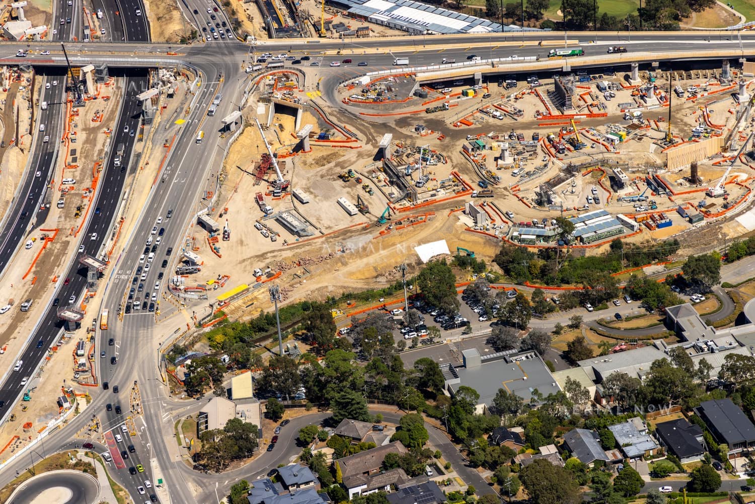 Aerial view of North East Link construction works in Bulleen, showing major road lanes, traffic, work zones, cranes and nearby residential streets.