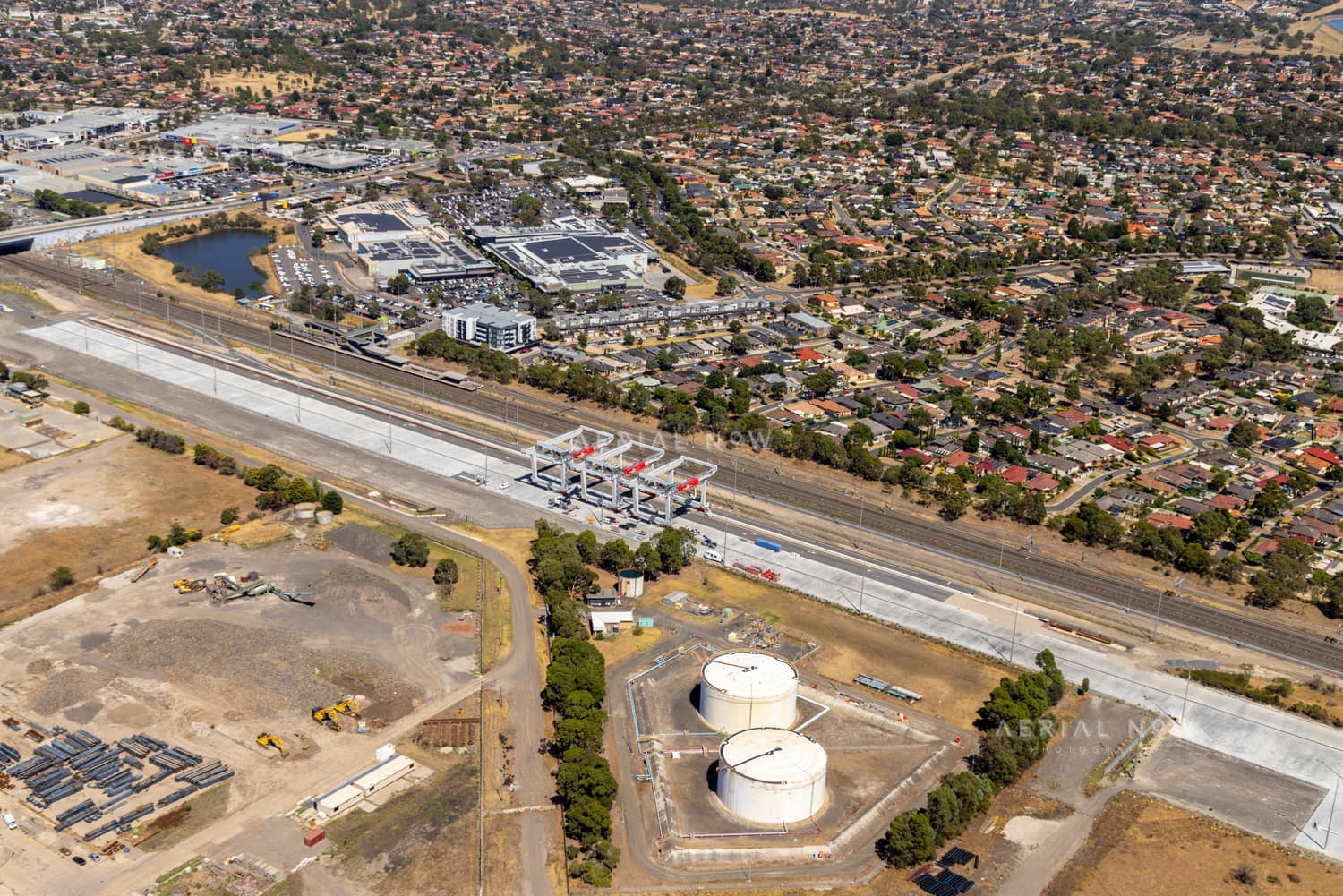 Aerial view of Union Road rail corridor construction in Somerton VIC, with concrete works, rail lines, nearby industrial tanks, commercial buildings and surrounding residential streets.