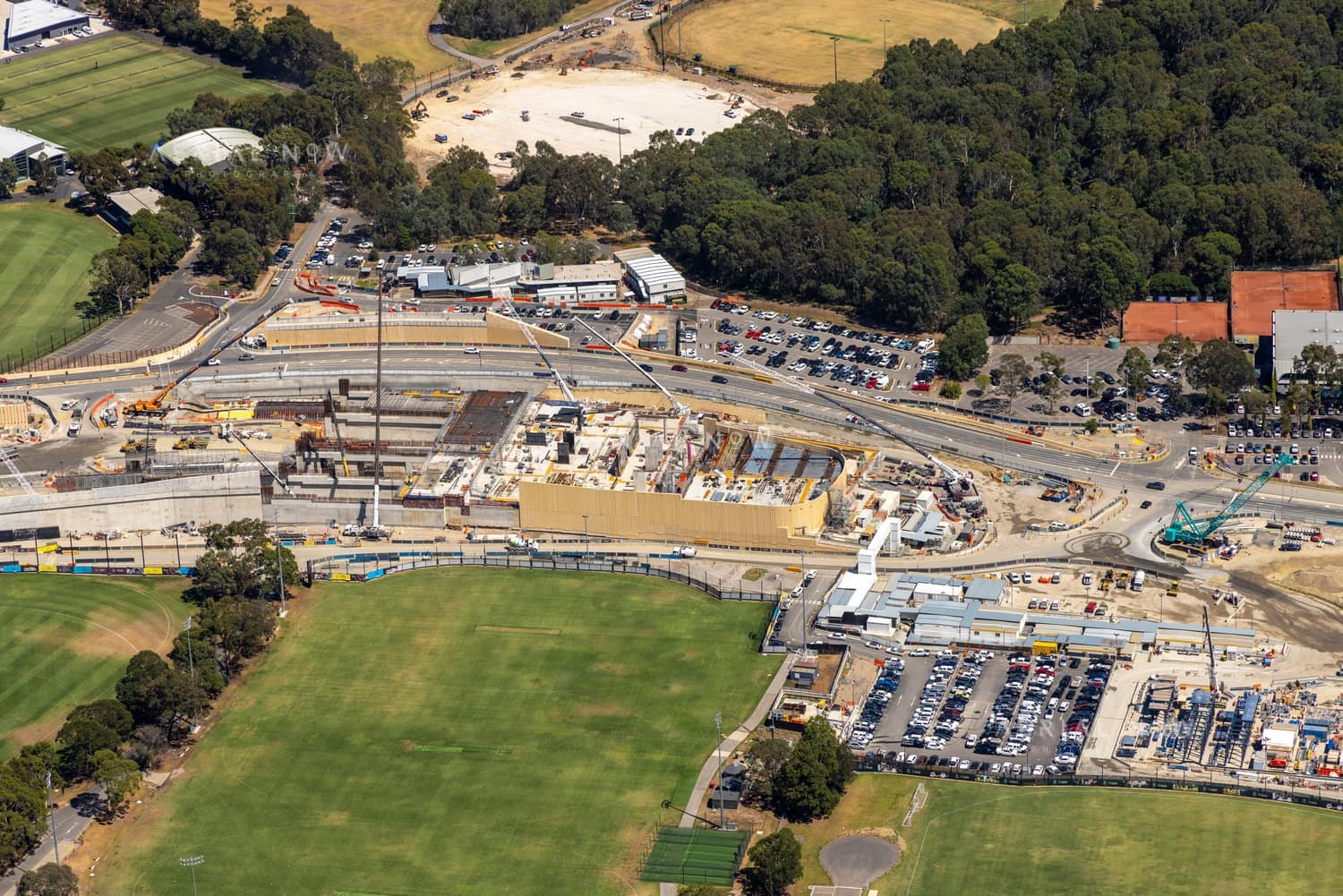 Aerial view of North East Link construction works with road infrastructure, work zones, car parks and sports fields in Bulleen, Victoria.