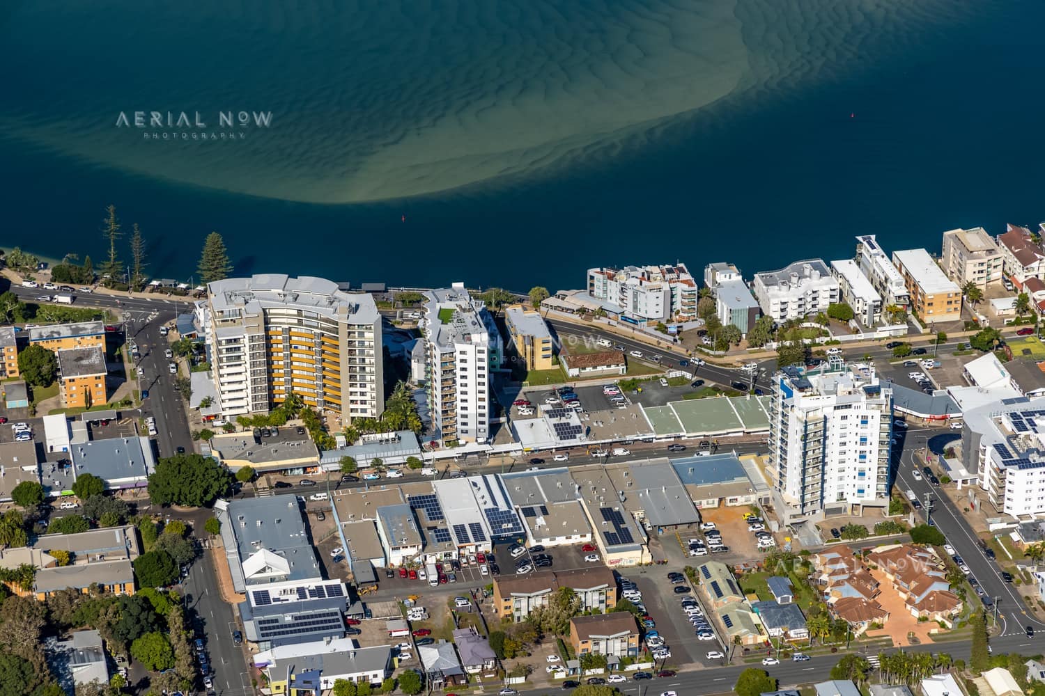 Aerial view of waterfront apartments and streets beside Pumicestone Passage in central Caloundra, Queensland.