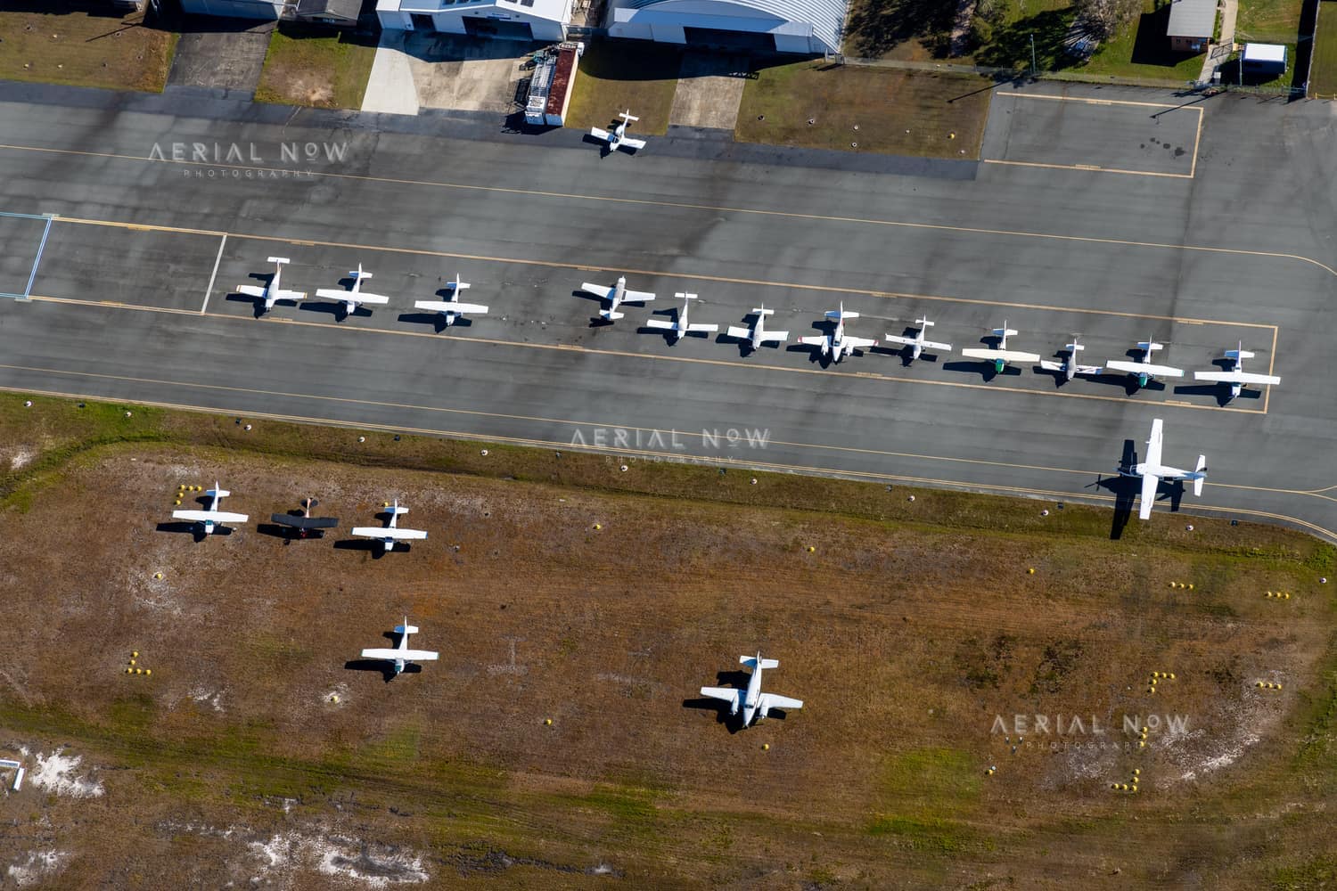 Aerial view of light aircraft parked on the apron and grass beside hangars at Caloundra Airport in Caloundra West, Queensland.
