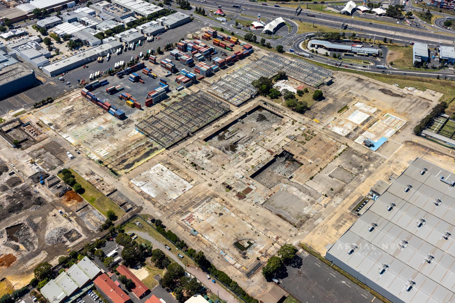 Aerial view of the former General Motors Holden factory redevelopment site, with dismantled structures, container storage and the West Gate Freeway in Port Melbourne, Victoria.