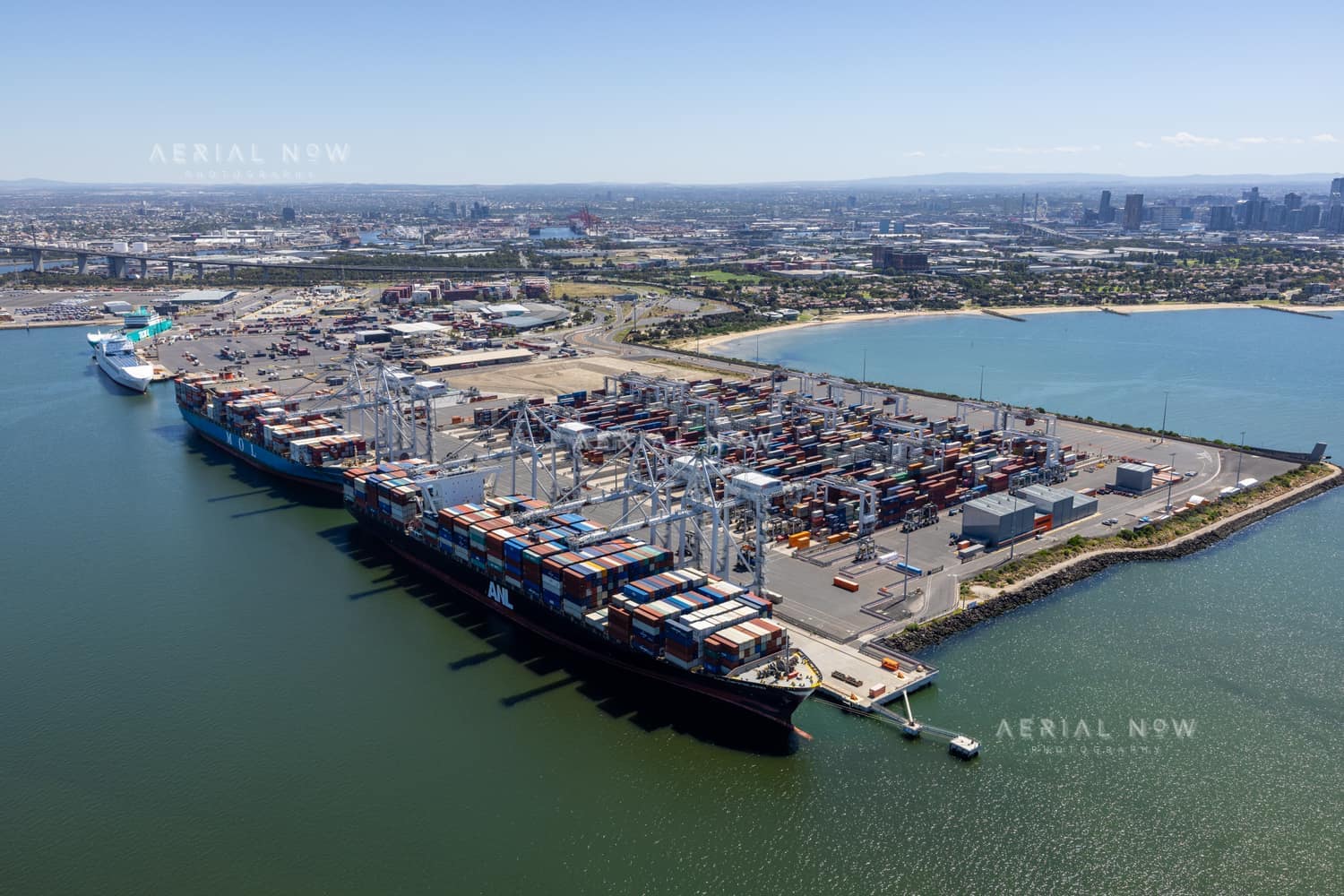 Aerial view of container ships alongside Webb Dock East, with cranes, container stacks and Port Phillip Bay at Port Melbourne in February 2022.