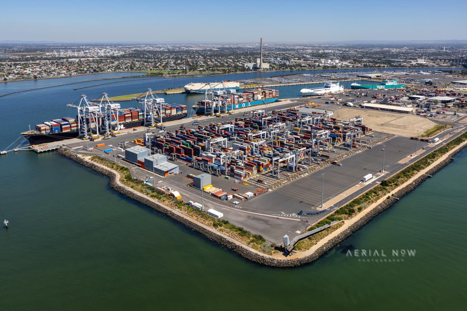 Aerial view of Webb Dock container terminal in Port Melbourne, showing container stacks, gantry cranes, wharves and surrounding bay waters.