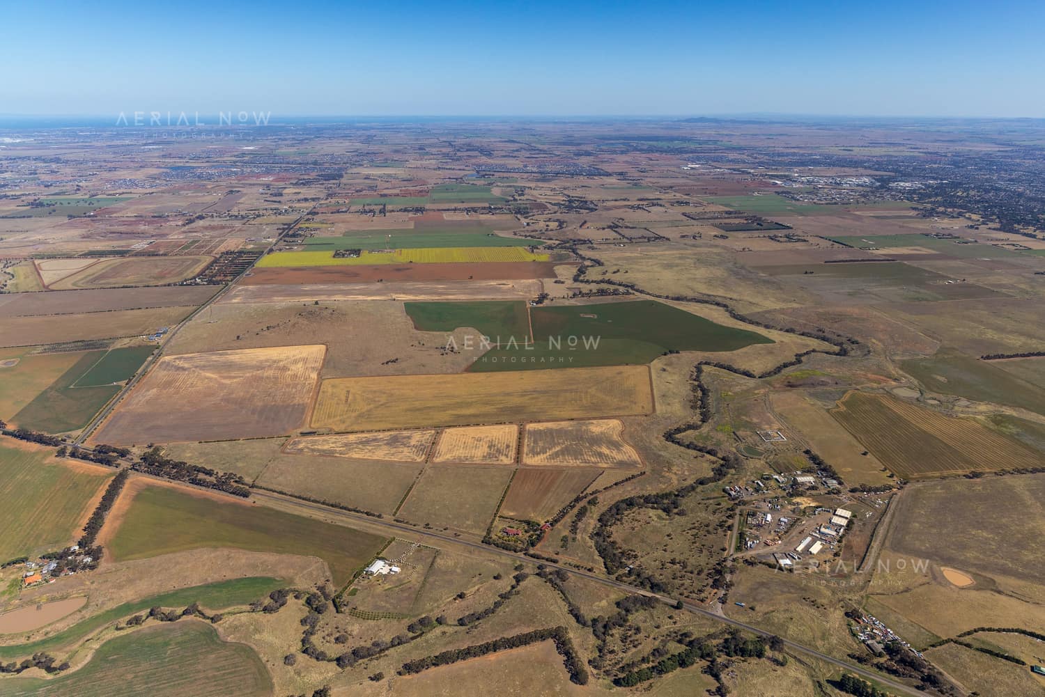 Aerial view of farmland and paddocks around Mount Cottrell Road in Melton, Victoria, with rural properties, access roads and dry agricultural land stretching to the horizon.