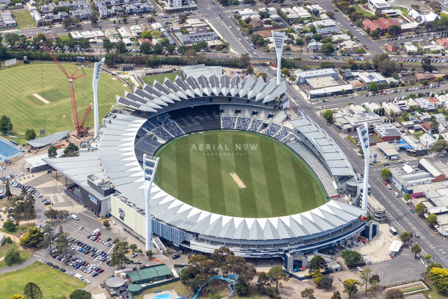 Aerial view of GMHBA Stadium at Kardinia Park in South Geelong, with the oval, grandstands, light towers, surrounding streets and nearby urban blocks visible.