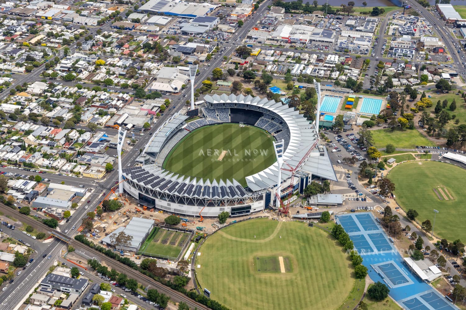 Aerial view of GMHBA Stadium in Kardinia Park, South Geelong, showing the oval, grandstands, nearby cricket grounds, tennis courts, car parks and surrounding streets.