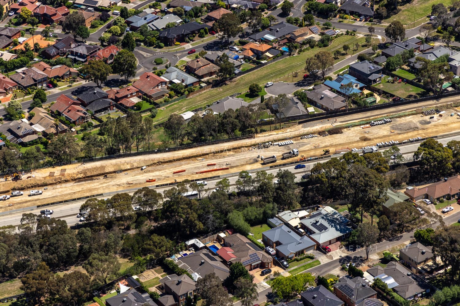 Aerial view of the North East Link construction corridor running beside suburban homes in Watsonia North, Victoria.