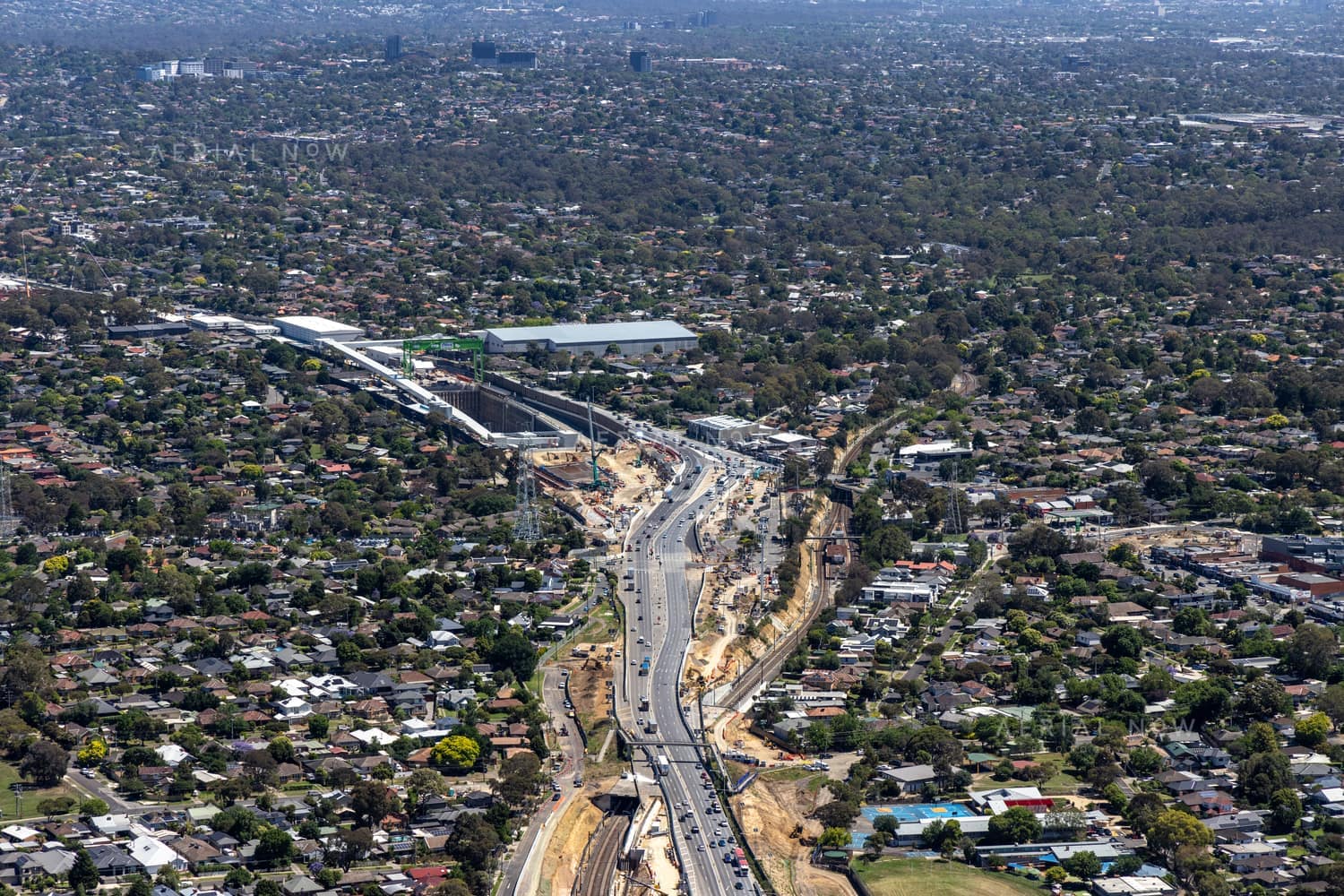 Aerial view of North East Link construction works along Greensborough Road in Watsonia, with traffic, earthworks and surrounding suburban homes.