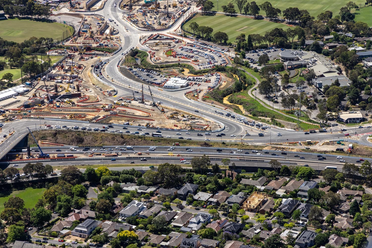 Aerial view of North East Link construction works beside the Eastern Freeway in Balwyn North, with traffic, roadworks, residential streets and sports fields visible.