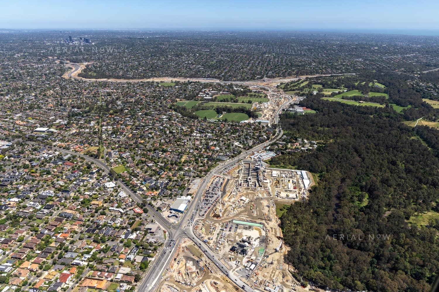 Aerial view of North East Link construction works in Bulleen VIC, with major road works, excavation areas, residential streets and surrounding parkland visible.