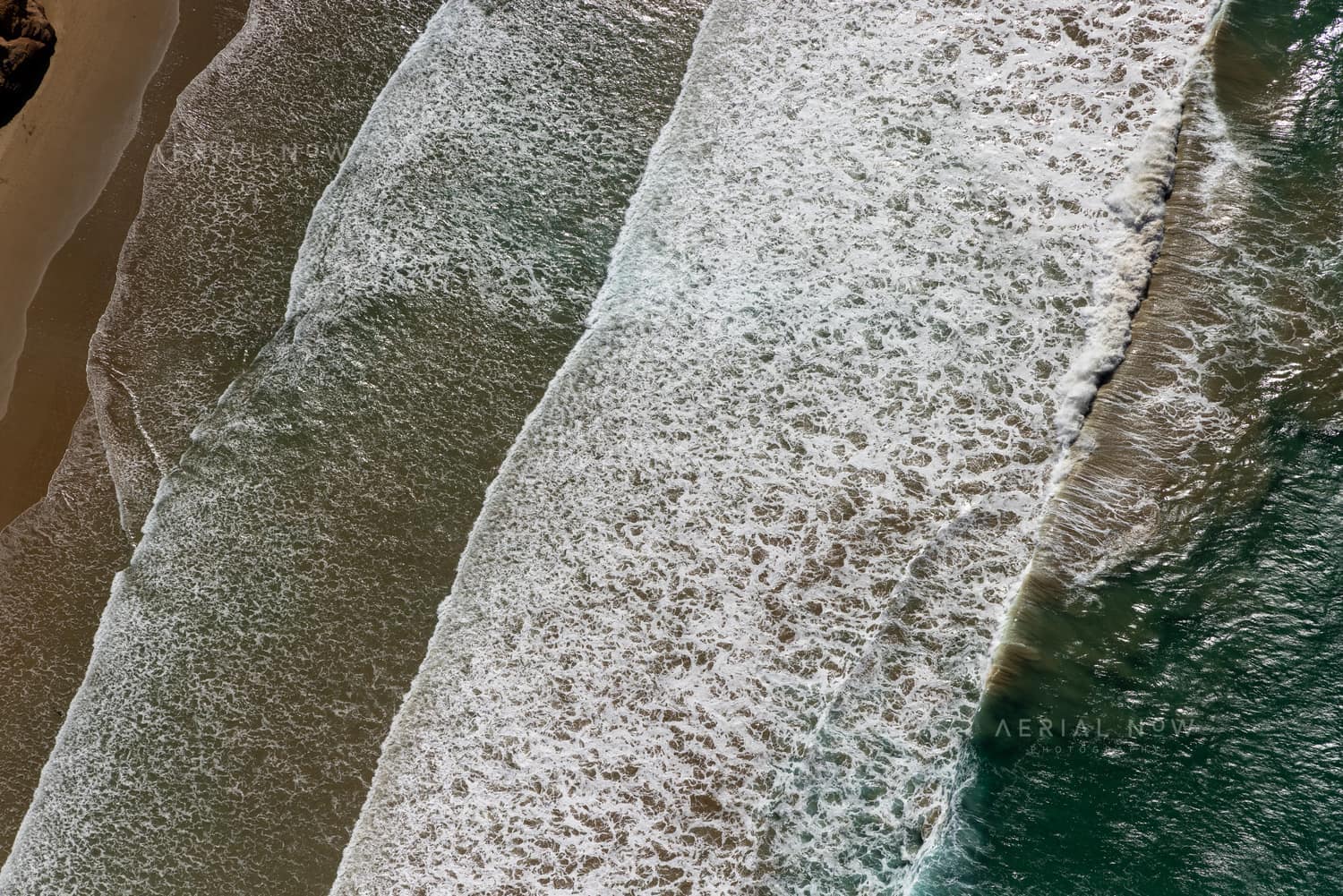 Aerial view of white surf lines breaking over a sandy shoreline near Anglesea on the Victorian coast.