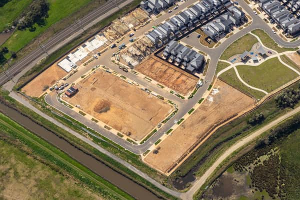 Aerial view of Casey Green Estate construction at Loosestrife Street, Narre Warren, showing timber-framed townhouses, serviced lots, new streets, parkland, a drainage channel and adjacent rail corridor.
