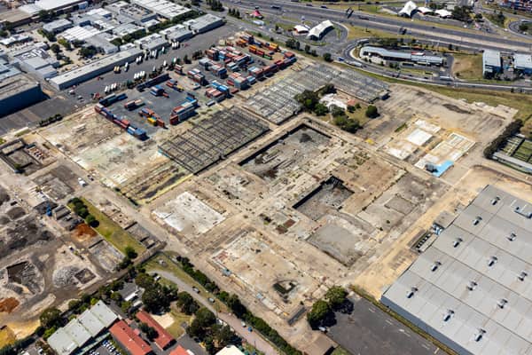Aerial view of the former General Motors Holden factory redevelopment site, with dismantled structures, container storage and the West Gate Freeway in Port Melbourne, Victoria.