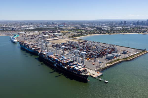 Aerial view of container ships alongside Webb Dock East, with cranes, container stacks and Port Phillip Bay at Port Melbourne in February 2022.
