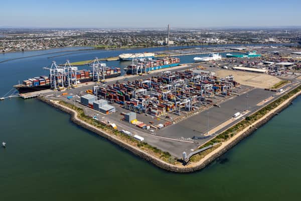 Aerial view of Webb Dock container terminal in Port Melbourne, showing container stacks, gantry cranes, wharves and surrounding bay waters.