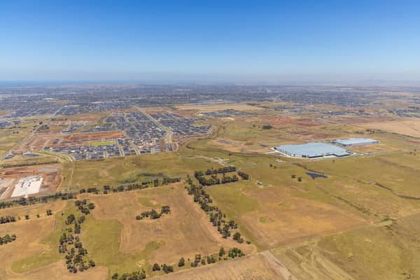 Wide aerial view over Boundary Road in Truganina, showing established warehouses, expanding housing estates, open farmland and the future Djeembana logistics precinct in Melbourne's west.