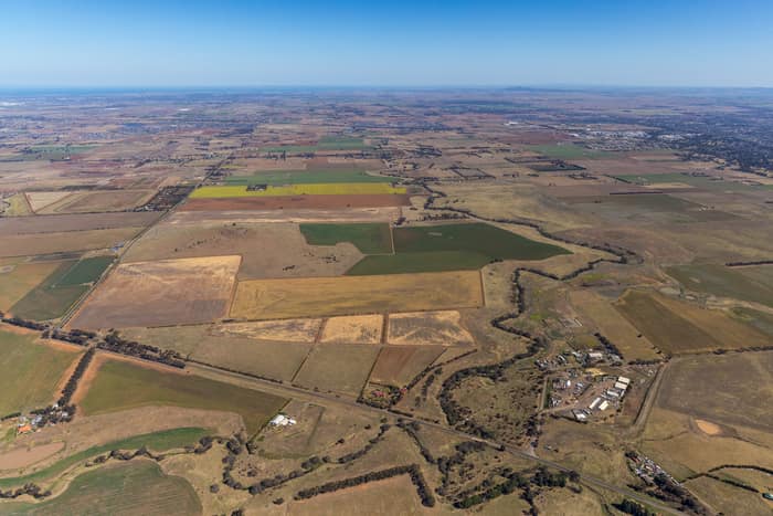 Aerial view of farmland and paddocks around Mount Cottrell Road in Melton, Victoria, with rural properties, access roads and dry agricultural land stretching to the horizon.