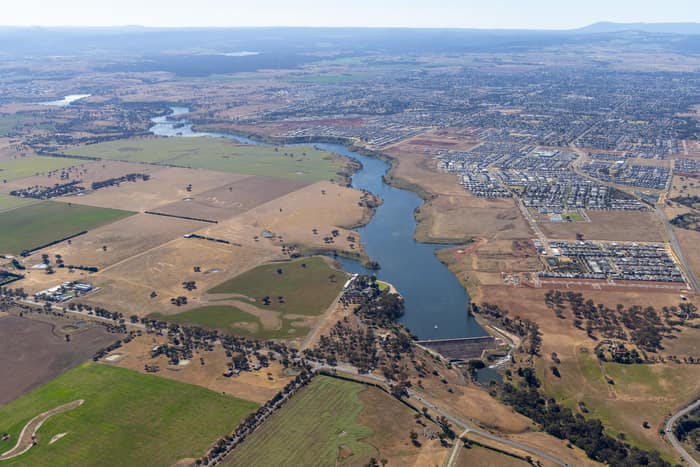 Aerial view of Melton Reservoir and the Werribee River near Melton VIC, with farmland, new housing estates and rural roads surrounding the water.