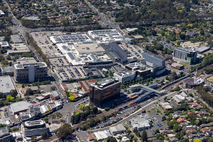 Aerial view of Eastland Shopping Centre in Ringwood VIC, showing the large retail complex, rooftop areas, car parks, surrounding roads, nearby offices and the Ringwood Station rail corridor.