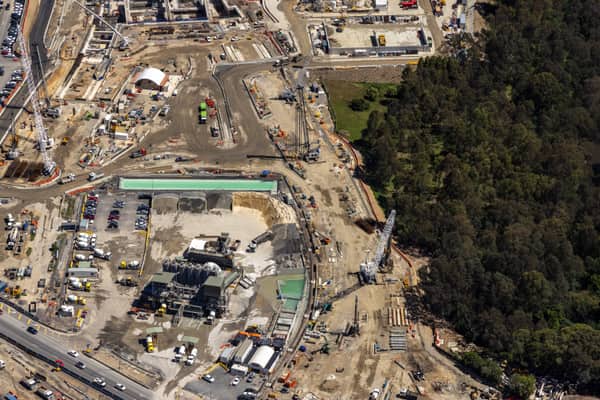 Aerial view of the North East Link construction compound in Bulleen, with cranes, earthworks, equipment yards and adjacent bushland.