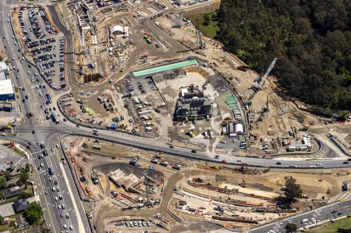 Aerial view of North East Link construction works in Bulleen, with major roadworks, cranes, machinery, site compounds and traffic on surrounding arterial roads.