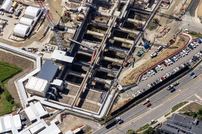 Aerial view of the North East Link construction site beside Bulleen Road in Bulleen, showing excavated concrete works, cranes, machinery, parked vehicles and traffic.