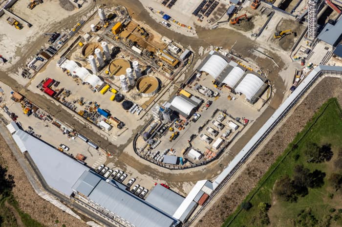 Aerial view of the North East Link construction site in Bulleen showing work sheds, silos, machinery, access roads and equipment within a large compound.
