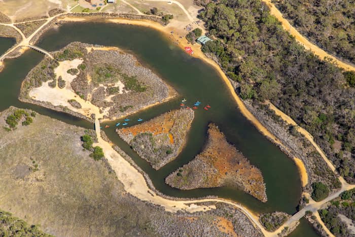 Aerial view of Coogoorah Park and the Anglesea River wetlands in Anglesea VIC, with kayaks on winding waterways, sandy banks, islands, tracks and surrounding bushland.