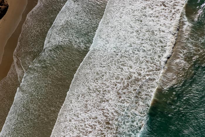 Aerial view of white surf lines breaking over a sandy shoreline near Anglesea on the Victorian coast.