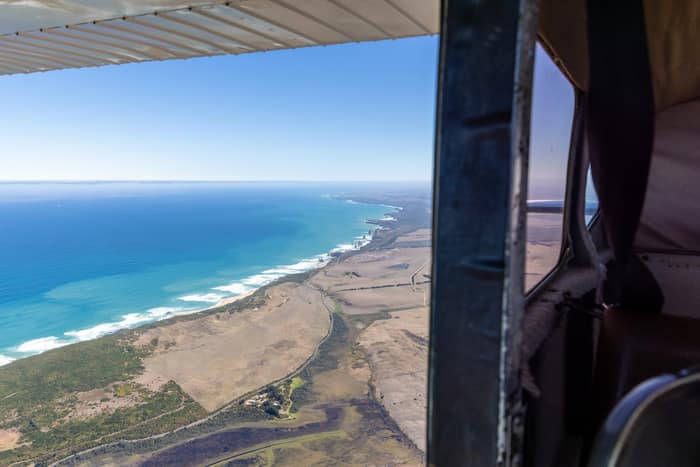 Aerial view of the Princetown coastline and Southern Ocean in Victoria, with surf beaches, dunes, farmland and part of the aircraft visible.