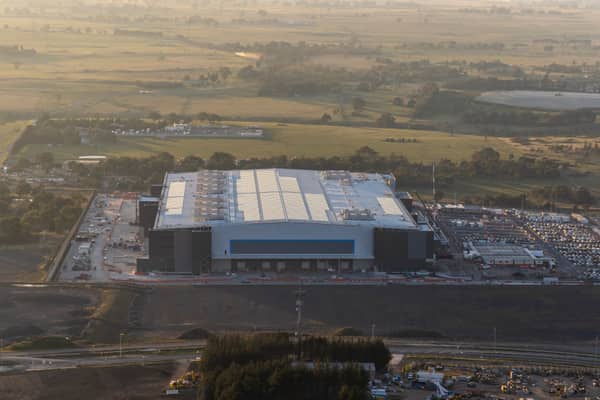 Aerial view of the Amazon Robotics Fulfilment Centre under construction in Craigieburn, with a large warehouse building, loading areas, staff parking and surrounding rural land.